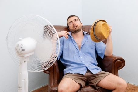 Hot man sitting in front of fan because he needs a heat pump!