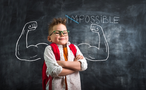 Boy in front of chalkboard with big muscle drawing