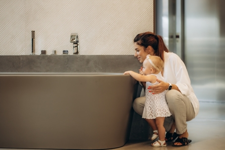 mother with young girl looking inside bathtub