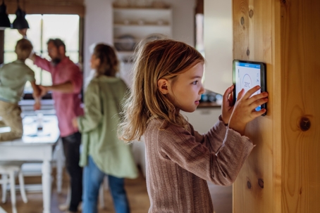 little girl programming a modern thermostat