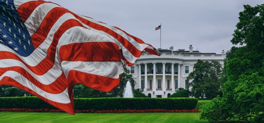 White House with flag fluttering in left foreground