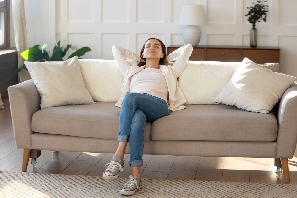 woman lounging on couch, arms behind head, not really knowing about air quality
