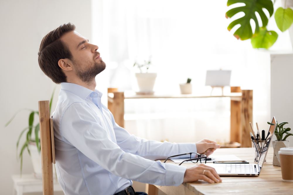 man at desk taking deep relaxing breaths