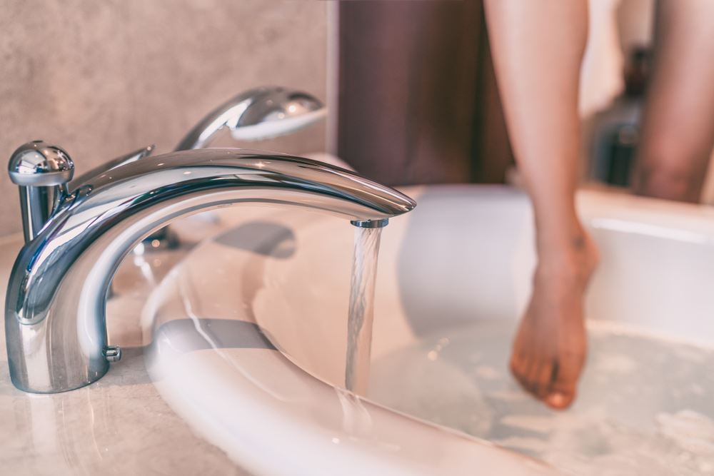 woman dipping toe into bathtub water