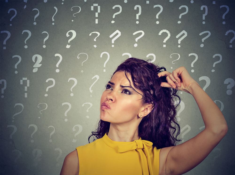 woman scratching her head with question marks all around
