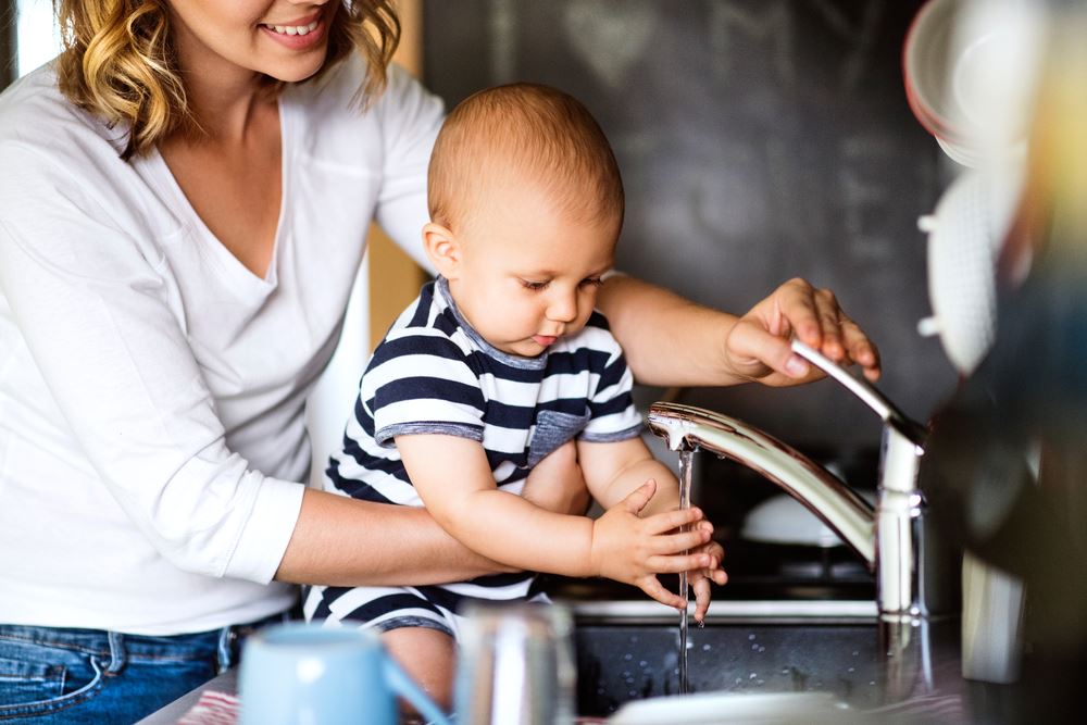 mother and baby washing hands at kitchen sink