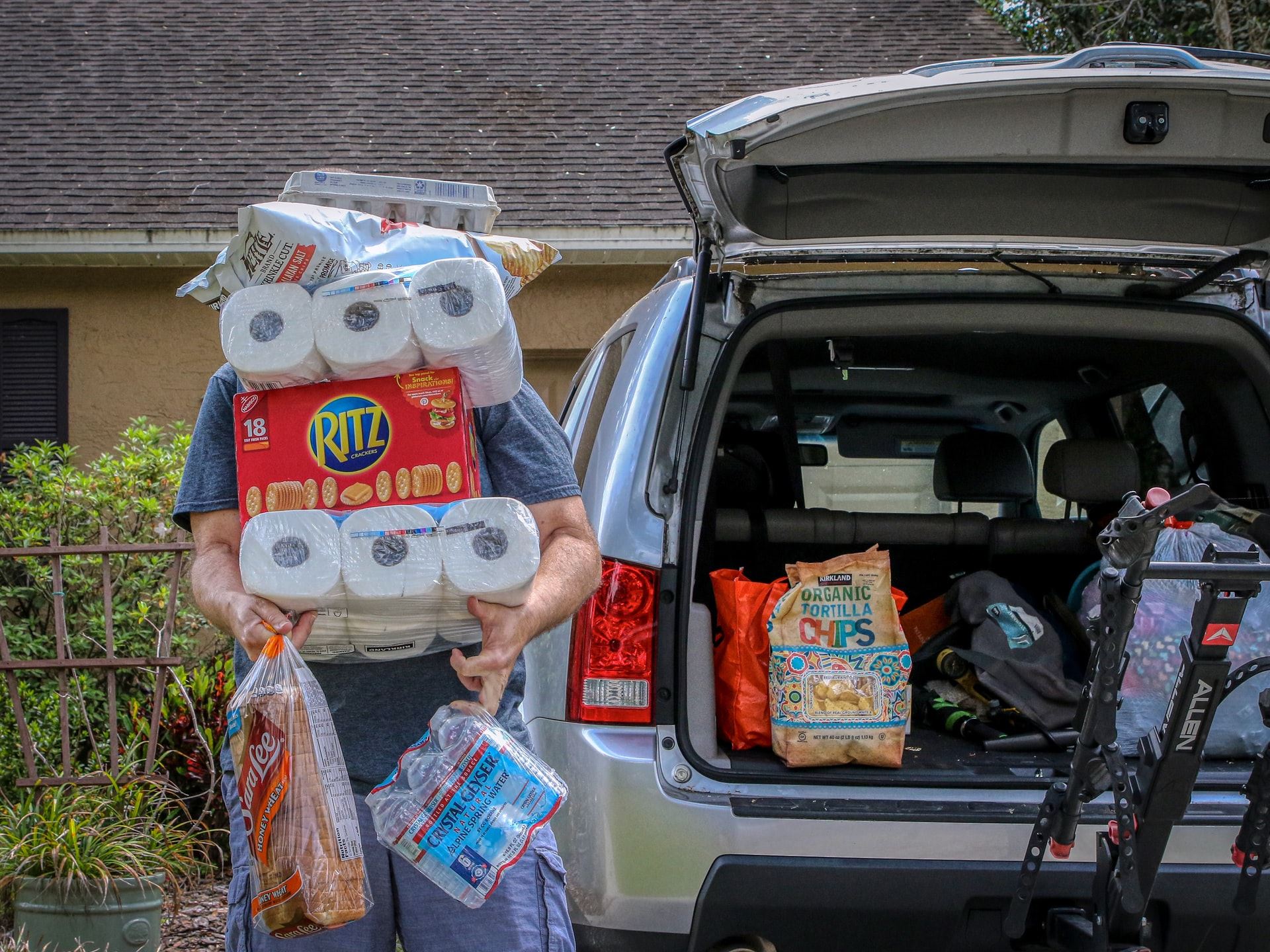 Man carrying in groceries with two packs of toilet paper