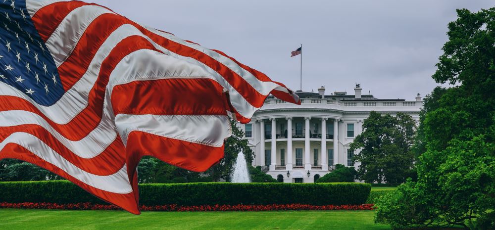 white house with large flag fluttering in left foreground